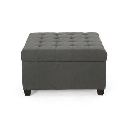 The Isabella Contemporary Ottoman With Storage features a square dark gray upholstered design, tufted button top, and short black legs, shown from the front against a white background.