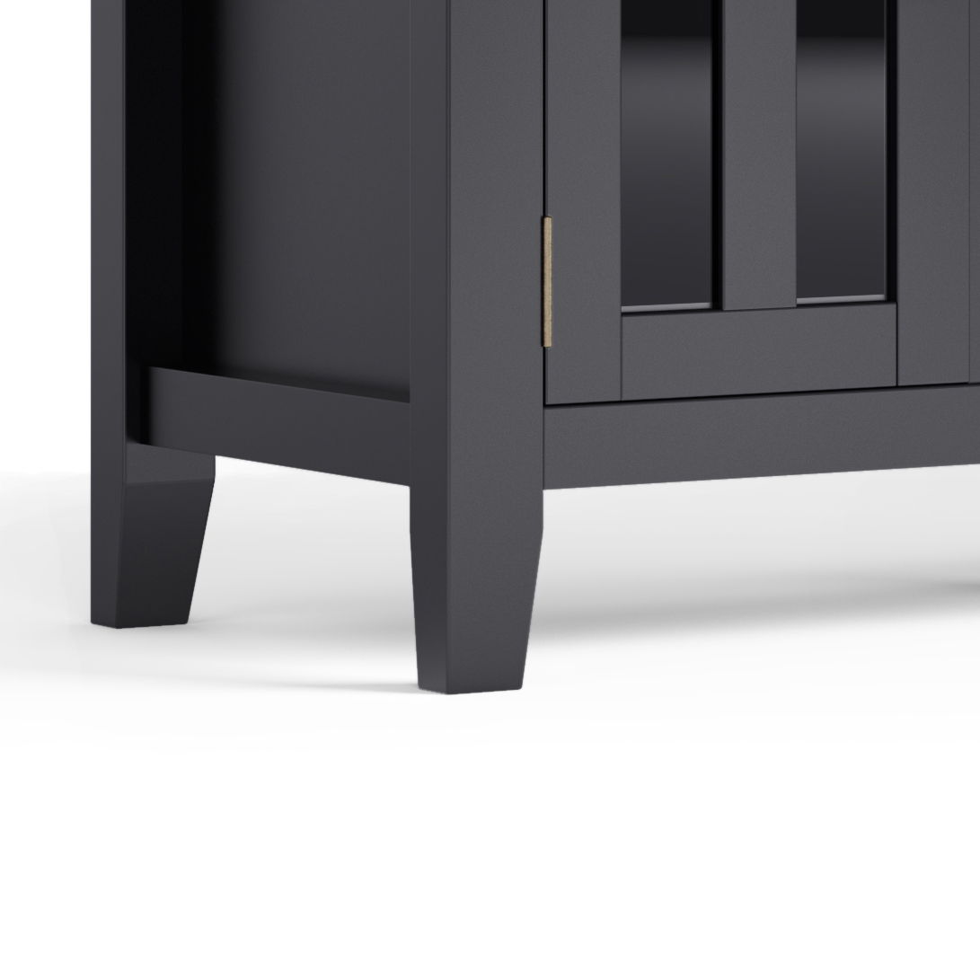 Close-up of the bottom corner of the Artisan - TV Media Stand, a dark wooden cabinet with square legs and a paneled door, set against a plain white background.