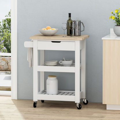 The Tattnall Kitchen Cart With Wheels features a wooden top, white body, drawer, two shelves, and black wheels. It holds a fruit bowl, two wine glasses, coffee pot, and jar. A towel hangs on the side; yellow flowers sit nearby on the counter.
