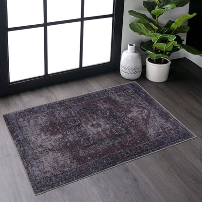 The Maval - Unique Washable Area Rug adds charm to gray wood floors near a large window. A potted plant and white decorative vase in the corner are brightened by natural sunlight.