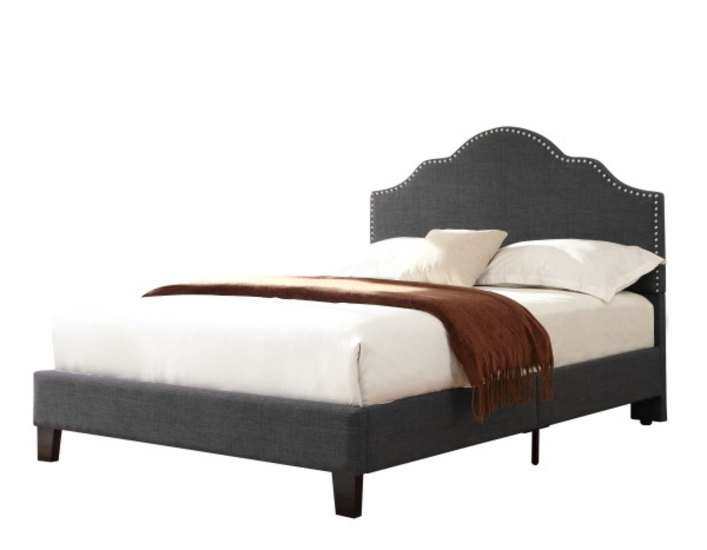 The Kopa - Fabric Upholstered Bed features a dark gray frame with a scalloped, studded headboard, styled with white bedding, two cream pillows, and a brown throw blanket against a plain white background.