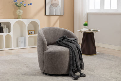 A Chenille Fabric Swivel Accent Armchair Barrel Chair with a dark knit blanket sits on a light rug. A small table nearby holds an open book and a plant, while shelves and wall art decorate the softly lit room.
