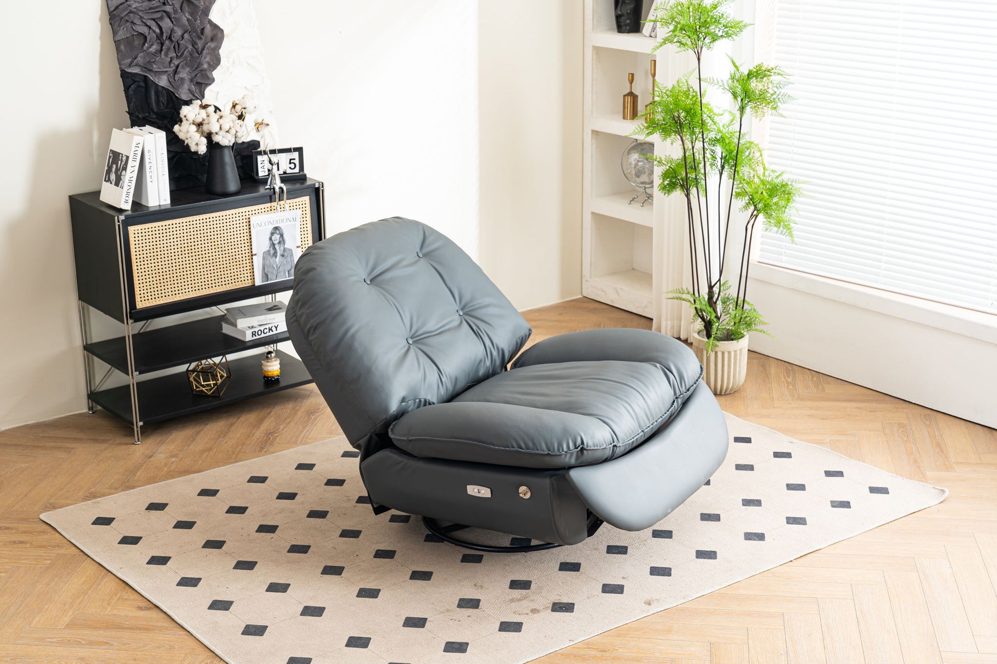 The Power Recliner Swivel Glider with USB Charger and Bluetooth Music Player sits on a patterned rug in a bright living room with wood floors, a black shelving unit, decor, and a green potted plant by the window.