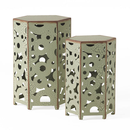 The Selva - Accent Table Set features two hexagonal side tables of different heights with a green, cracked finish and decorative cut-out circles and geometric shapes, shown side by side against a white background.