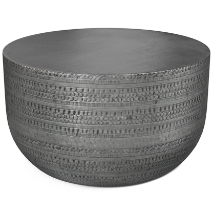 The Johnsen Handcrafted Metal Coffee Table features a round, flat top and textured sides with horizontal lines and circular indentations.