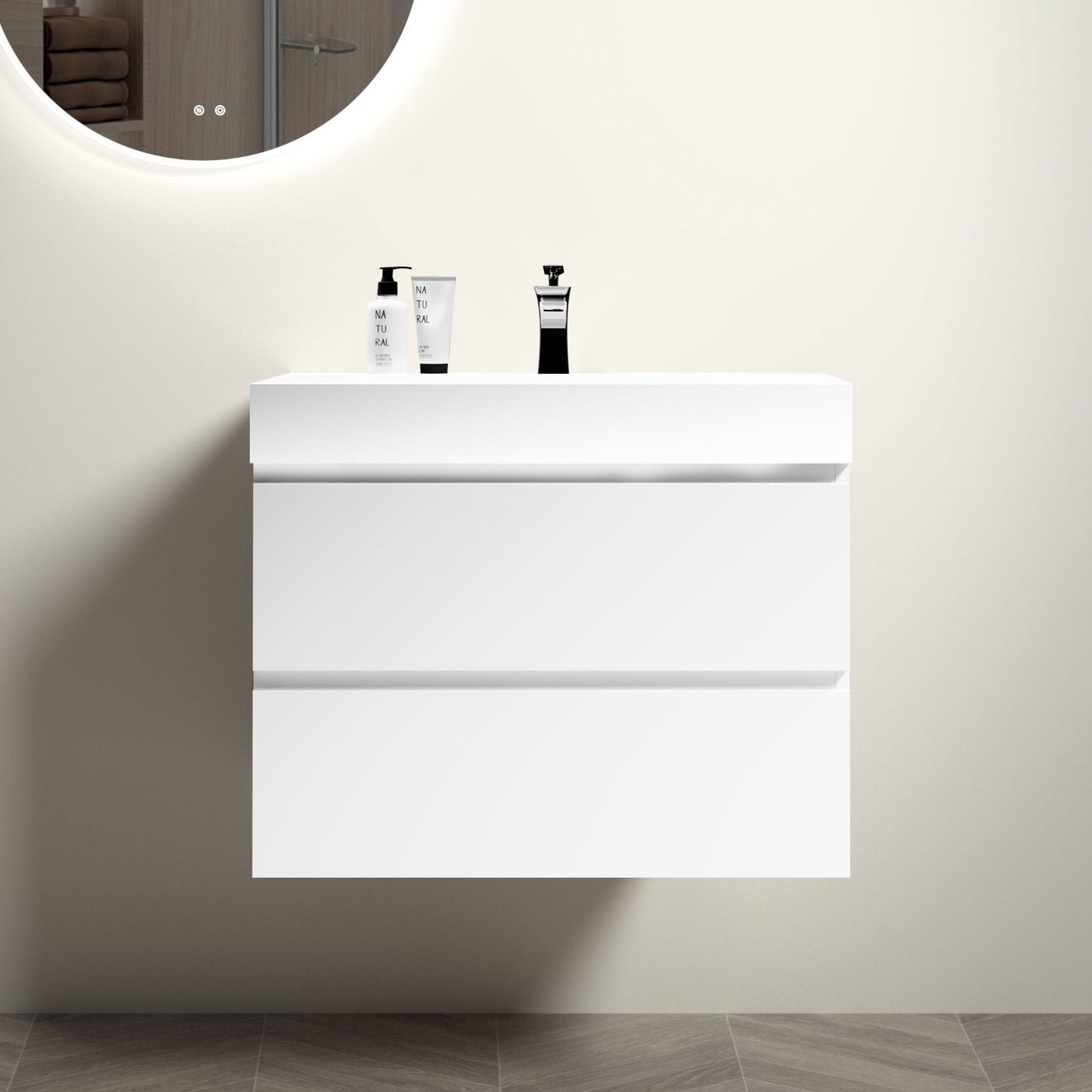 The Alice wall-mounted floating bathroom vanity features a modern, minimalist design with large storage and a one-piece sink basin (no drain or faucet), set against a light beige wall beneath a round illuminated mirror.