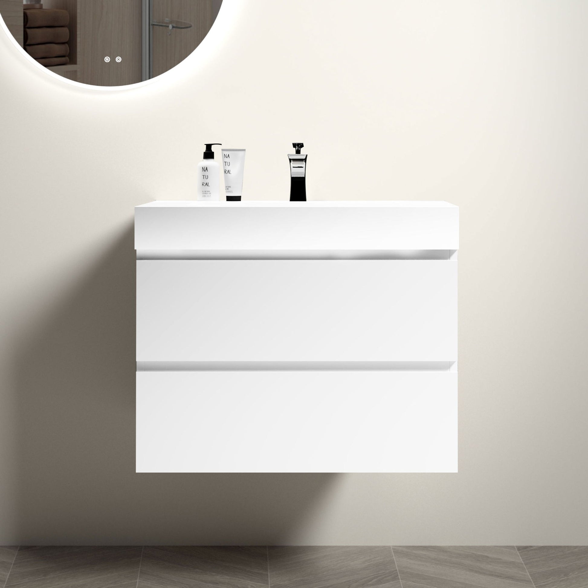 The Alice wall-mounted floating bathroom vanity features a modern, minimalist design with large storage and a one-piece sink basin (no drain or faucet), set against a light beige wall beneath a round illuminated mirror.