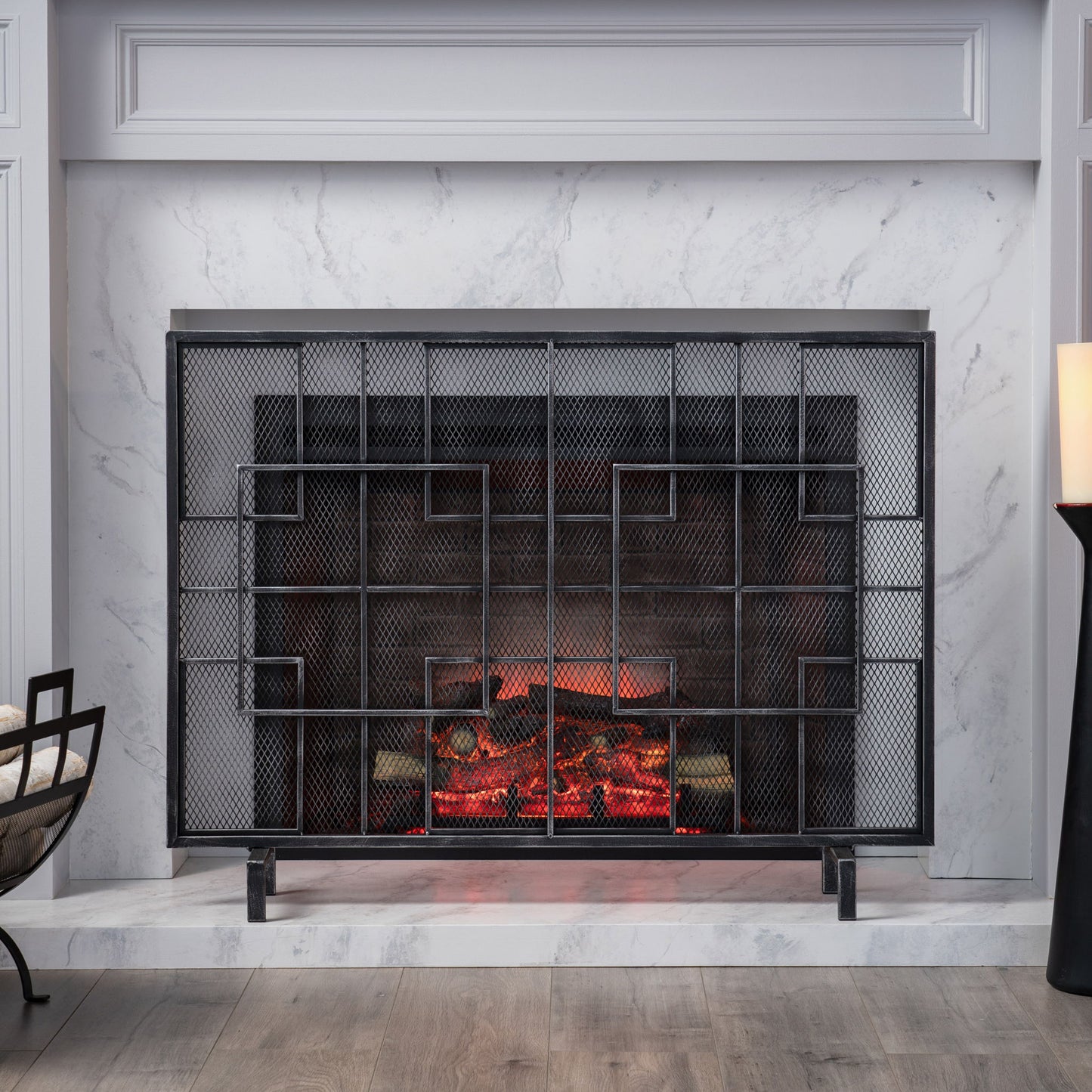 The Dorothy - Modern Single Panel Iron Fire Screen features a sleek black mesh with geometric designs, set against a white marble surround with gray veining. The warm fire creates a cozy, stylish atmosphere in the living space.