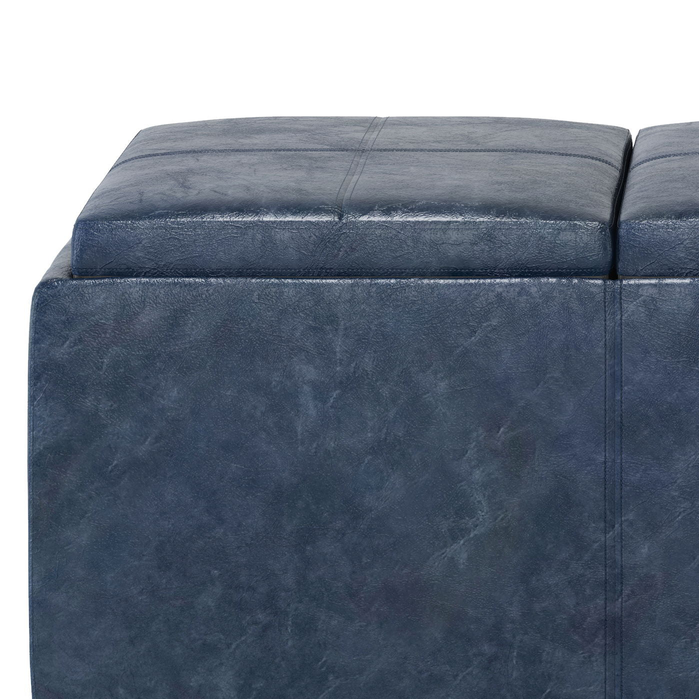 A close-up of the Avalon - Upholstered Storage Ottoman, featuring a dark blue, square design with a soft, textured leather-like surface and visible stitching on the cushion top.