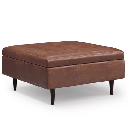 The Shay Large Square Coffee Table Storage Ottoman in brown leather features tufted detailing on top and dark wooden legs, shown on a white background.