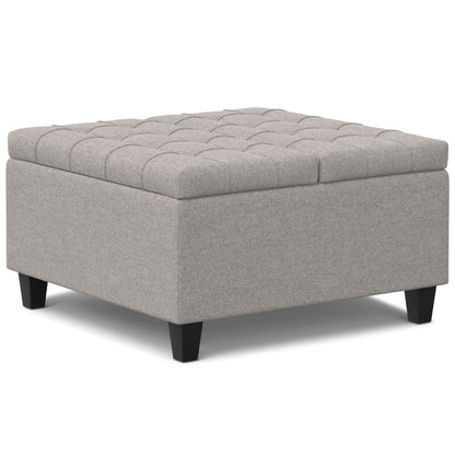 The Harrison - Upholstered Coffee Table Storage Ottoman features a square, light gray design with a tufted top and short black legs, shown against a white background.