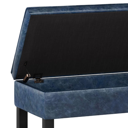 The Cosmopolitan Storage Ottoman Bench features a blue cushion, an open-bottom design, and a lift-up seat that reveals a black-lined storage compartment with a sturdy hinge mechanism.