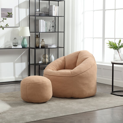 The Bedding Bean Bag Sofa Chair High Pressure Foam with Footrest, in tan, sits on a beige rug in a bright, modern living room. Behind it, a black metal bookshelf displays books and decor beneath a sunlit window.