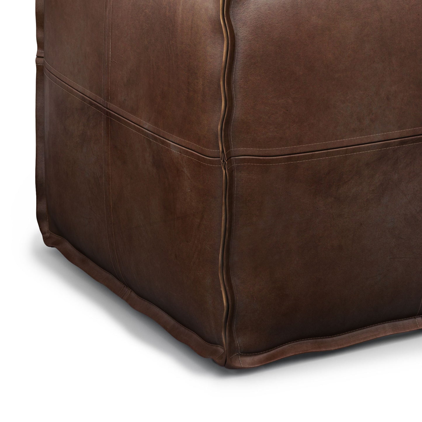 Close-up of the bottom corner of the Brody - Versatile Square Pouf in brown leather, highlighting visible seams, soft texture, and subtle creases. The pouf is positioned against a white background.