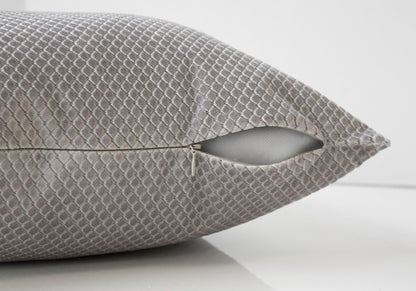 A close-up of a decorative gray modern square pillow with a diamond pattern, featuring a partially open zipper showing the hypoallergenic insert. The background is plain white.