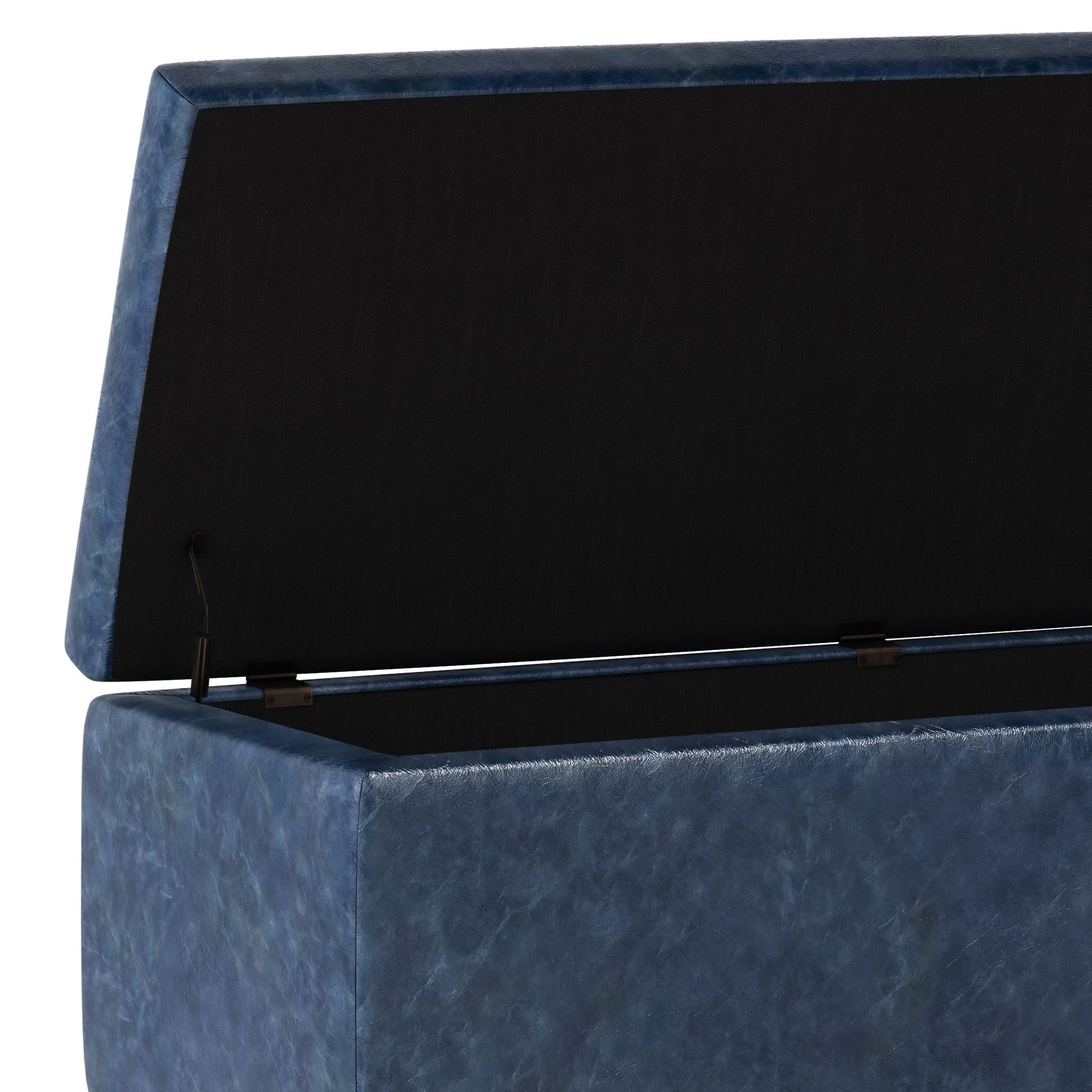 A close-up of the Hamilton - Upholstered Storage Ottoman in blue faux leather, shown with its cushioned lid open to reveal a spacious black interior. Hinges on each side support the lid.