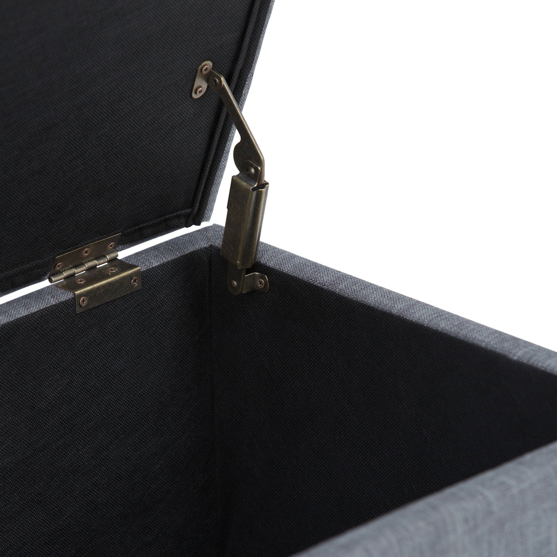 A close-up of the Sienna Upholstered Storage Ottoman Bench shows its open black fabric interior and metal hinge mechanism connecting the lid to the side.