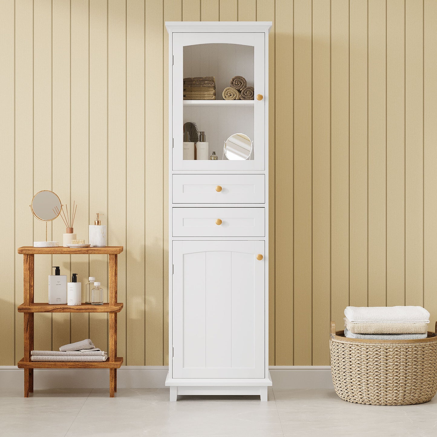 A Tall Bathroom Storage Cabinet With Glass Doors, free-standing with two drawers and adjustable shelves, made of painted MDF board for displaying your favorite items, stands against a beige paneled wall on a light tiled floor.