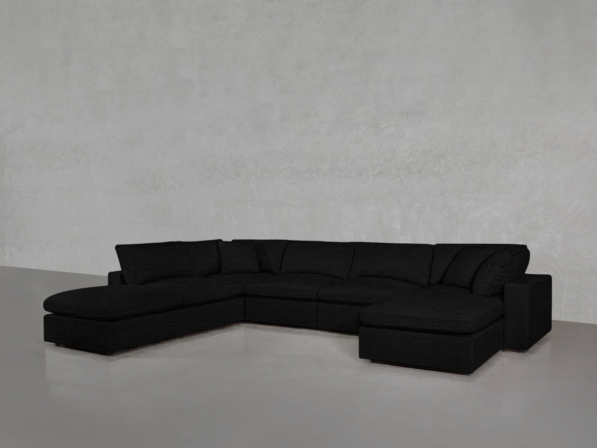 A 7-Seat Modular Chaise Corner Lounger Sectional in modern black sits on a light gray polished floor against a plain, textured gray wall.