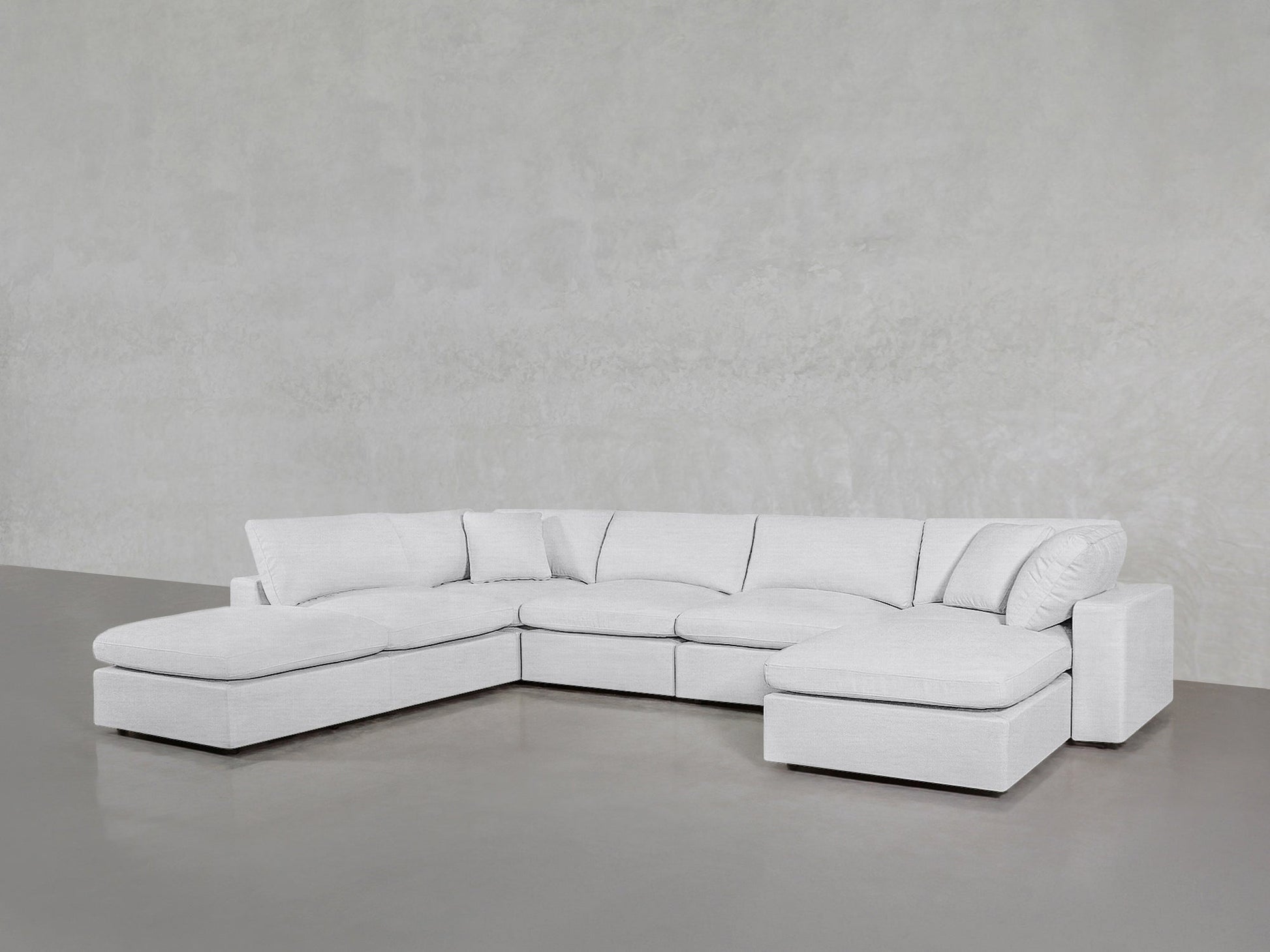 The 7-Seat Modular Chaise Corner Lounger Sectional in light gray features an L-shape, wide seats, multiple cushions, and sits on a shiny gray floor against a textured light gray wall.