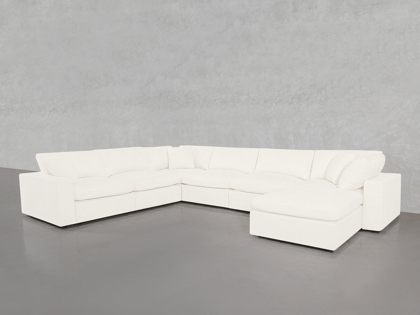 The 7-Seat Modular Chaise Corner Sectional, featuring thick cushions and a right-side chaise, is set on a gray floor against a light gray textured wall.