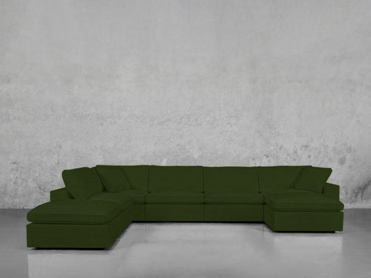 A 7-Seat Modular Chaise Corner Lounger Sectional in dark green with wide seats and cushioned backs is set against a plain light gray textured wall on a shiny gray floor.