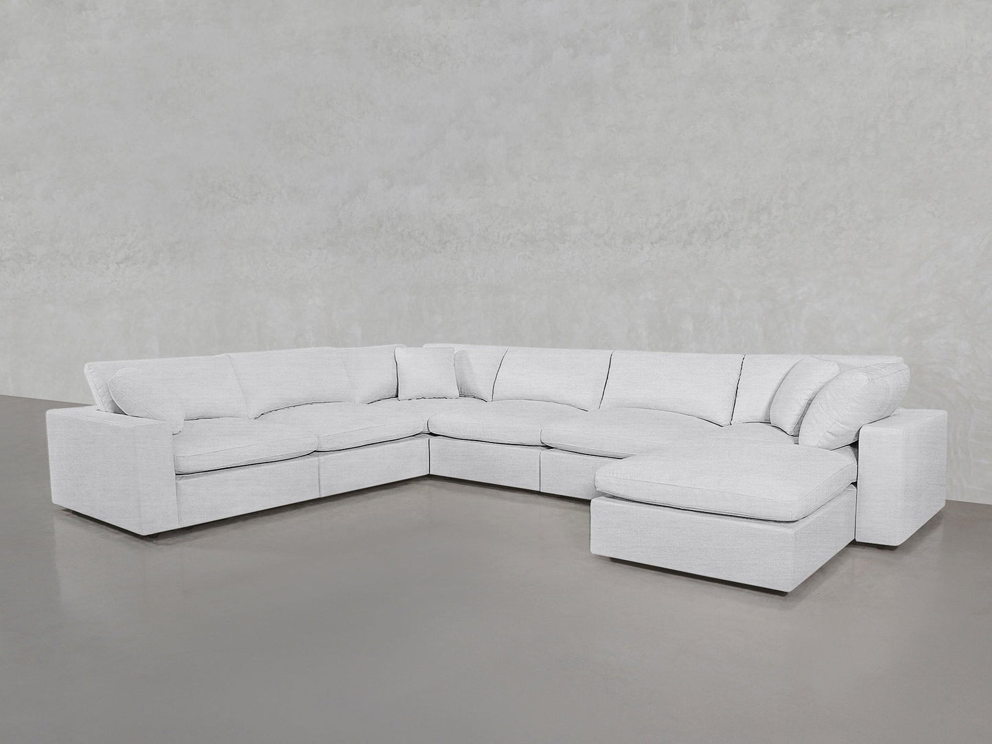 A spacious, modern white 7-Seat Modular Chaise Corner Sectional with a right-side chaise, set against light gray walls and flooring.