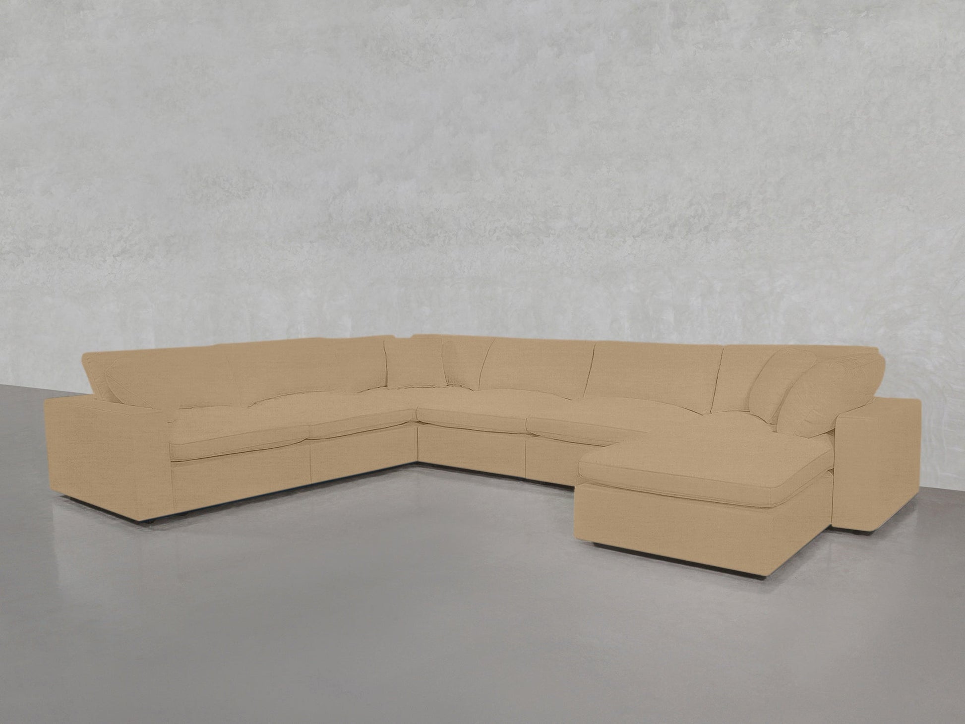 A 7-Seat Modular Chaise Corner Sectional with wide armrests is placed on a polished gray floor against a light gray textured wall.