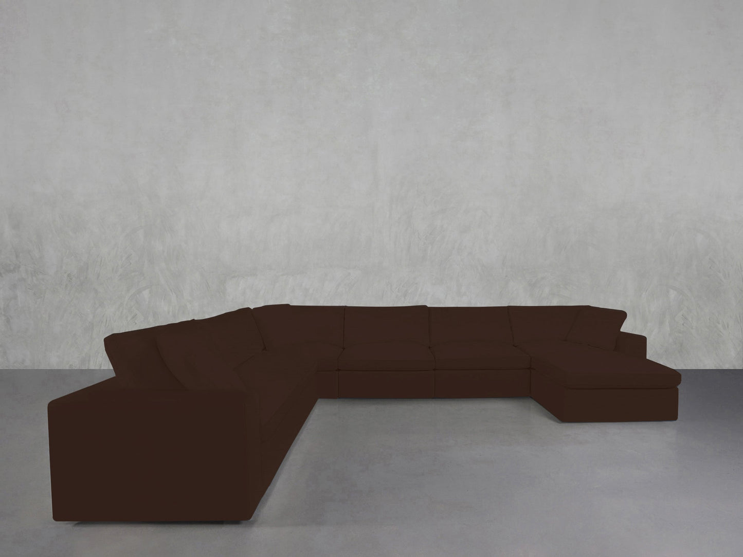 A 7-Seat Modular Chaise Corner Sectional in dark brown forms an L-shape against a plain, light gray textured wall on a smooth gray floor.