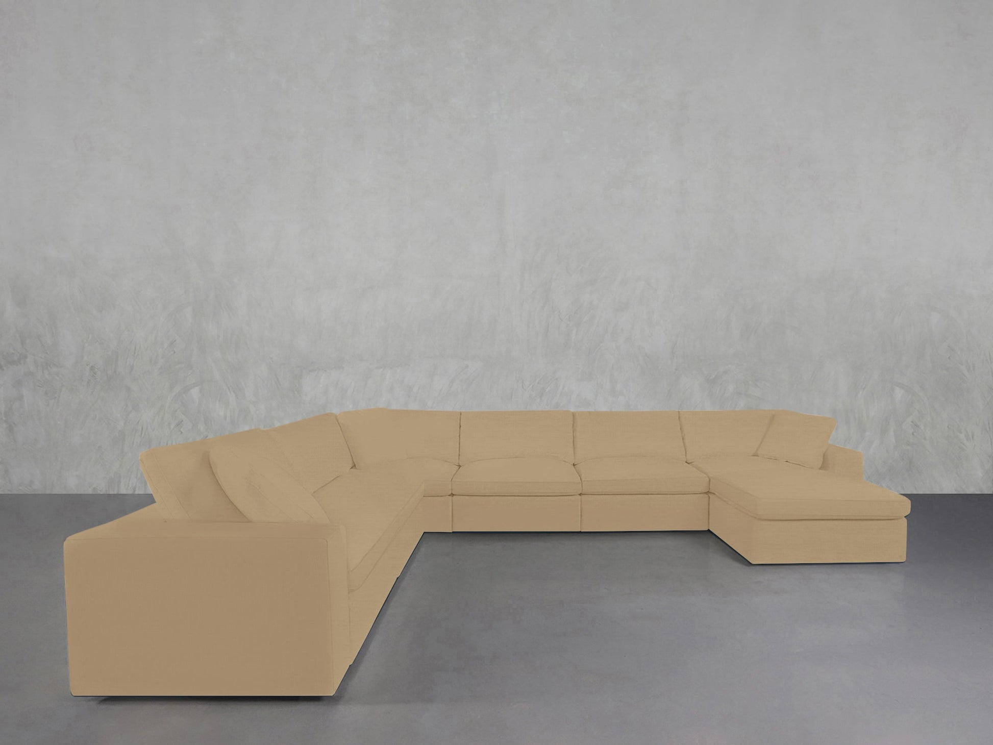 A spacious beige 7-Seat Modular Chaise Corner Sectional with plush cushions sits in a minimalist room featuring a smooth gray floor and a lightly textured wall background.