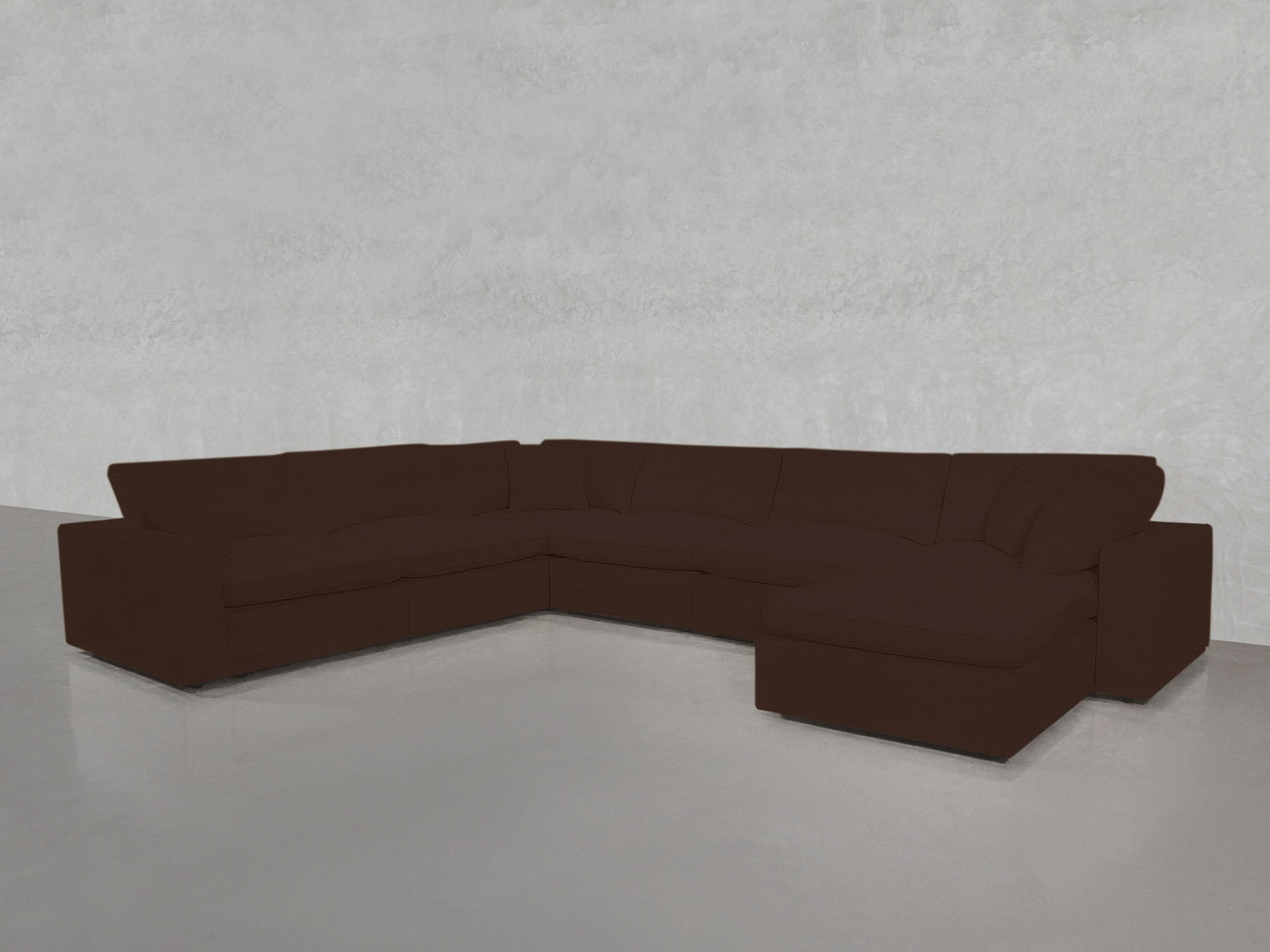 A spacious 7-Seat Modular Chaise Corner Sectional in dark brown, featuring plush cushions, sits in an empty room with light gray walls and a smooth, light floor.
