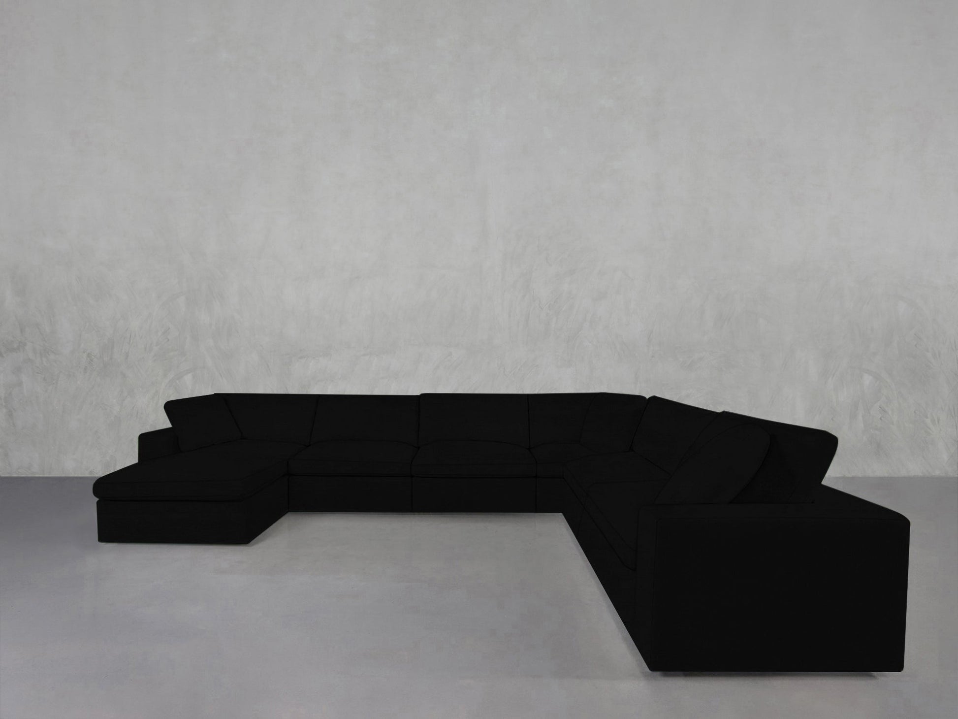 A spacious 7-Seat Modular Chaise Corner Sectional with clean, modern lines sits in a minimalist room featuring light gray walls and a smooth, light gray floor.