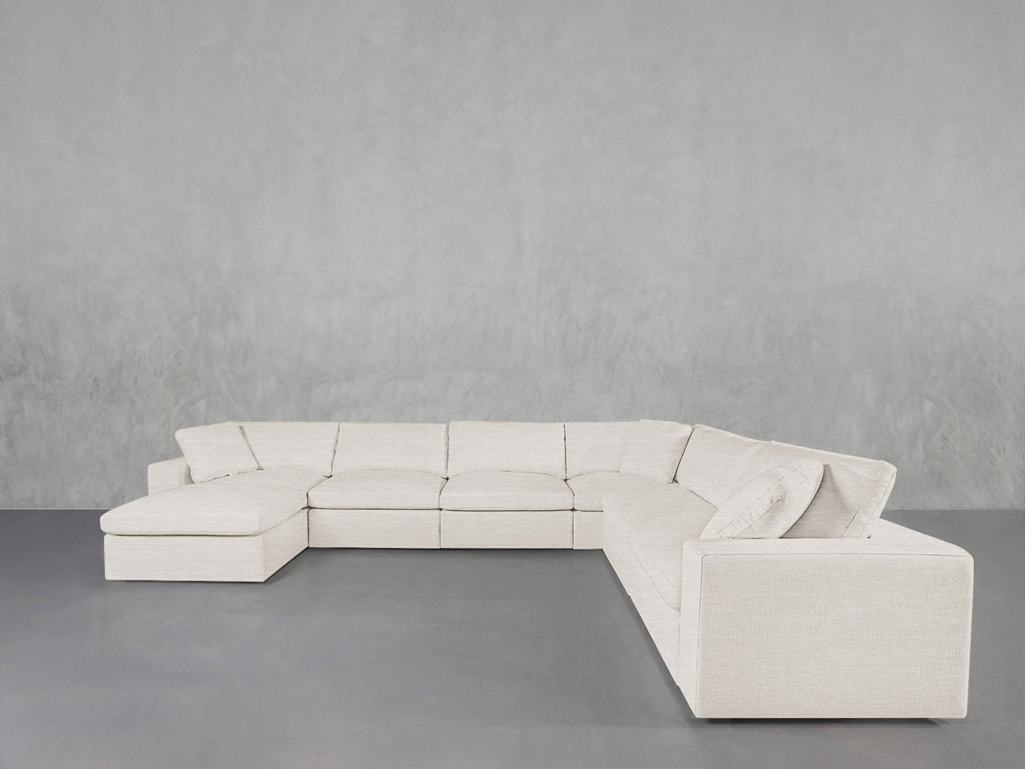The 7-Seat Modular Chaise Corner Sectional, in off-white, features a left-facing chaise and is set against a plain light gray wall with a gray floor.