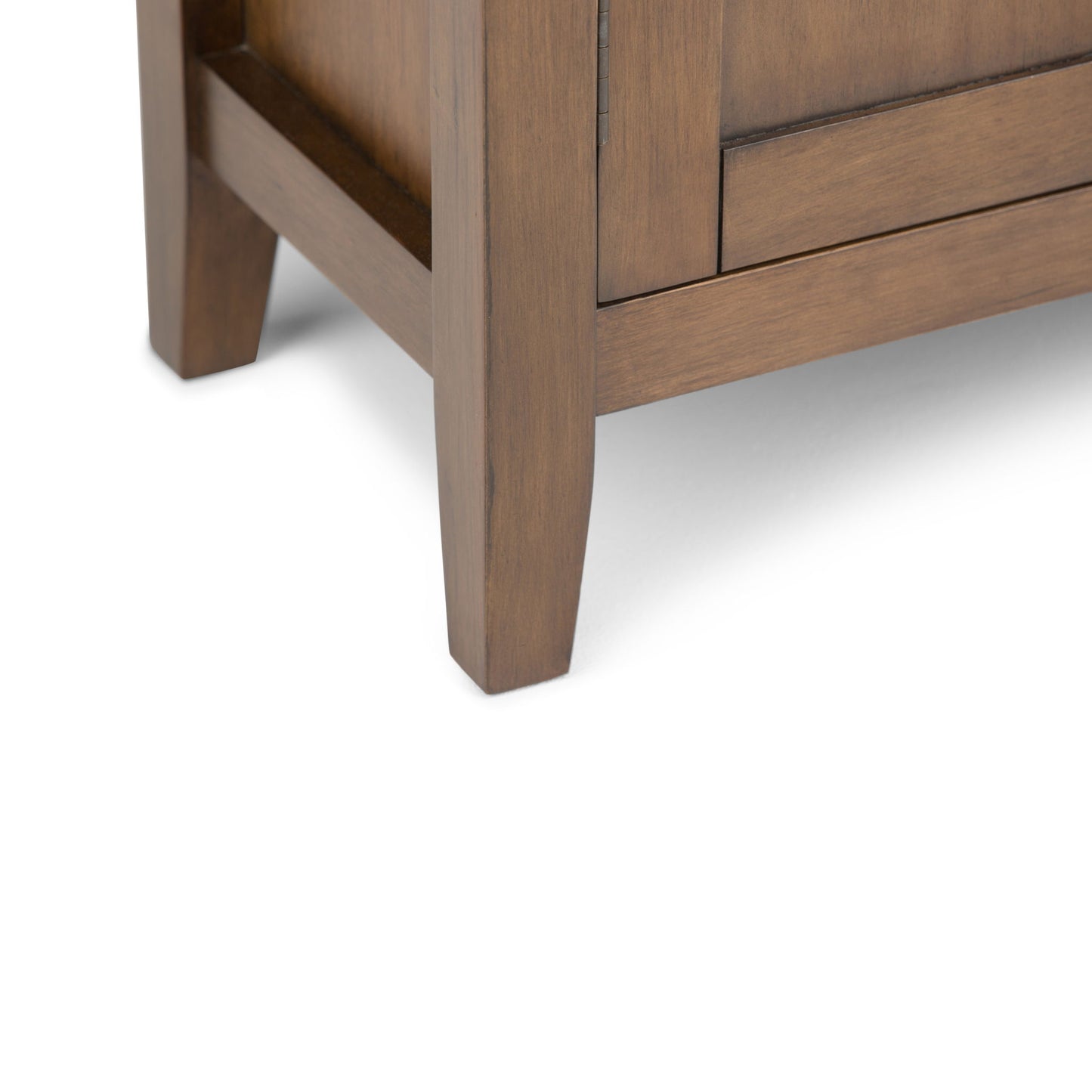 Close-up of the bottom corner of the Redmond - Handcrafted Low Storage Cabinet, showing two legs and part of a smooth brown finished panel against a white background.