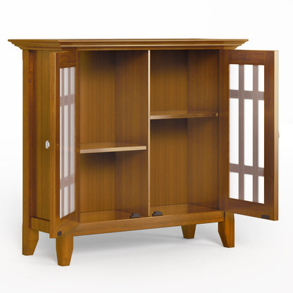 The Bedford - Storage Media Cabinet features glass-paneled doors that open to reveal two shelves and four compartments. With a natural wood finish, straight legs, and a simple modern design, it offers stylish storage for your media items.