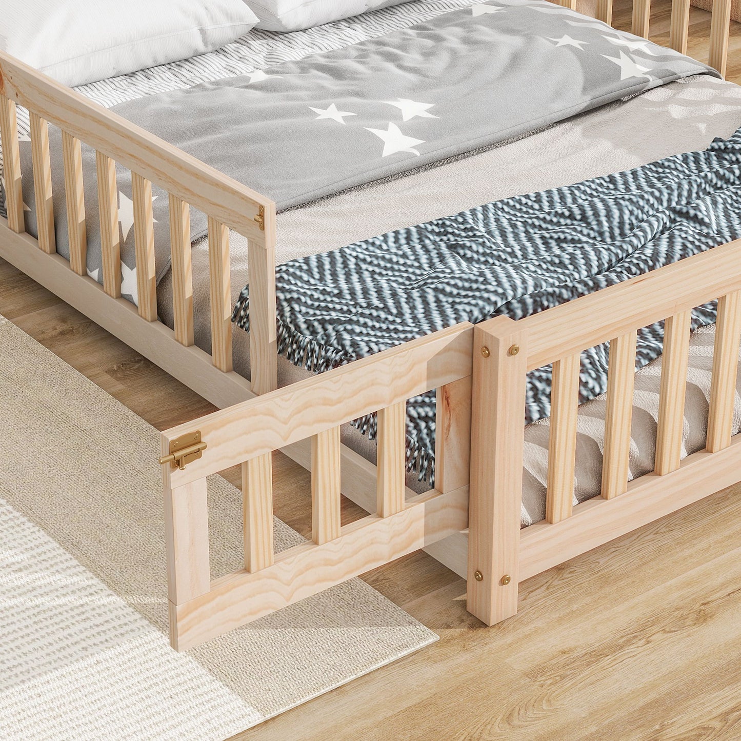 The House-Shaped Headboard Floor Bed With Fence sits on a light wood floor, made with a gray star-patterned blanket and blue zigzag throw. One guard rail is open, and a beige rug is partially visible beside the bed.