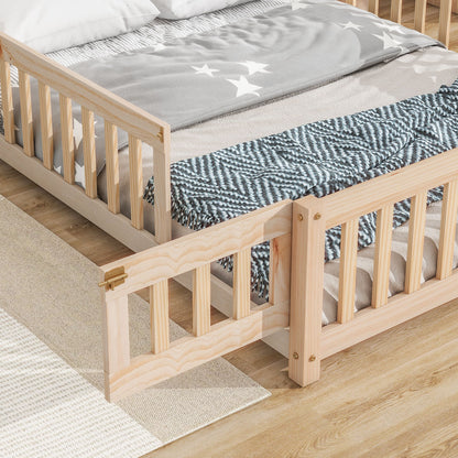 The House-Shaped Headboard Floor Bed With Fence sits on a light wood floor, made with a gray star-patterned blanket and blue zigzag throw. One guard rail is open, and a beige rug is partially visible beside the bed.
