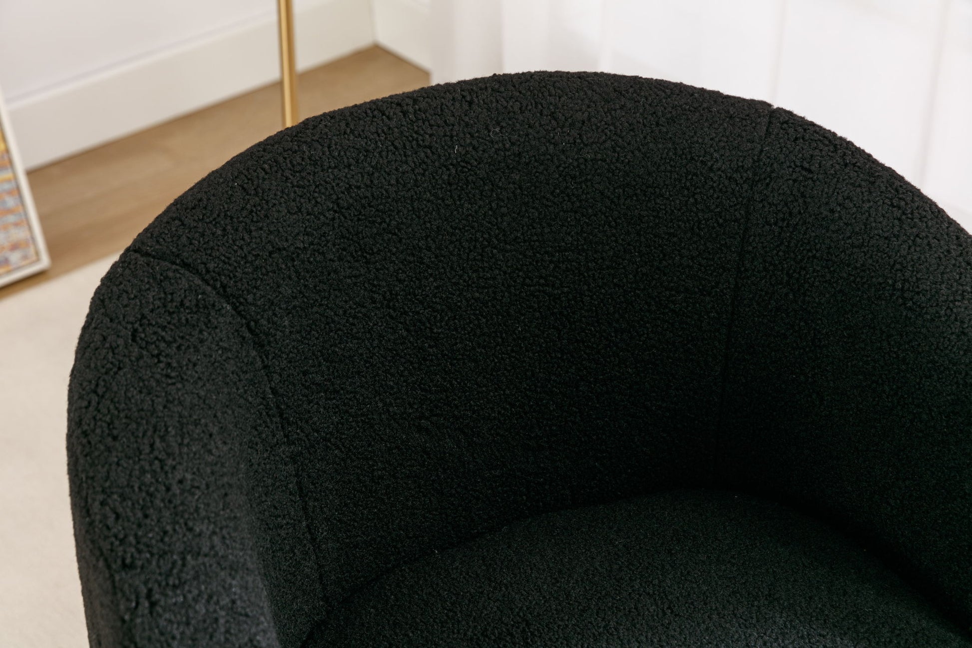 Close-up of the Teddy Fabric Swivel Accent Armchair Barrel Chair, featuring soft, textured teddy fabric and a sleek powder-coated metal ring base, set against light walls and a section of wooden floor.