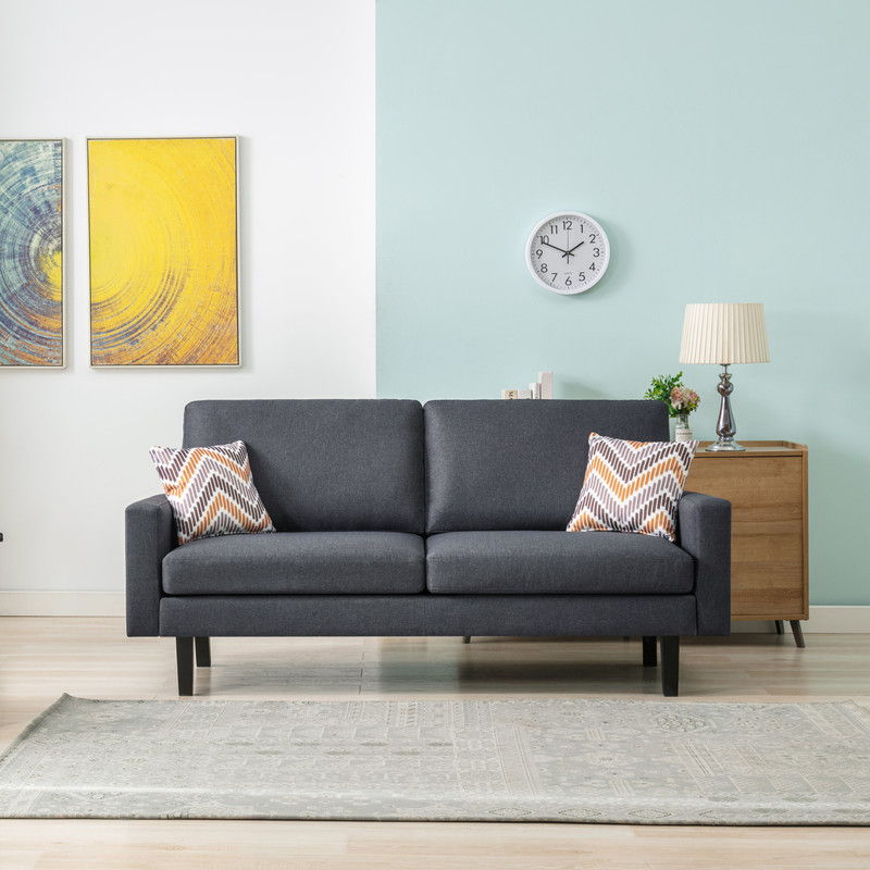 A modern living room featuring the Bahamas - Sofa Set With 2 Throw Pillows in dark gray, complemented by a light rug, two abstract yellow paintings, a round clock, and a wooden sideboard with a lamp and plant against white and blue walls.