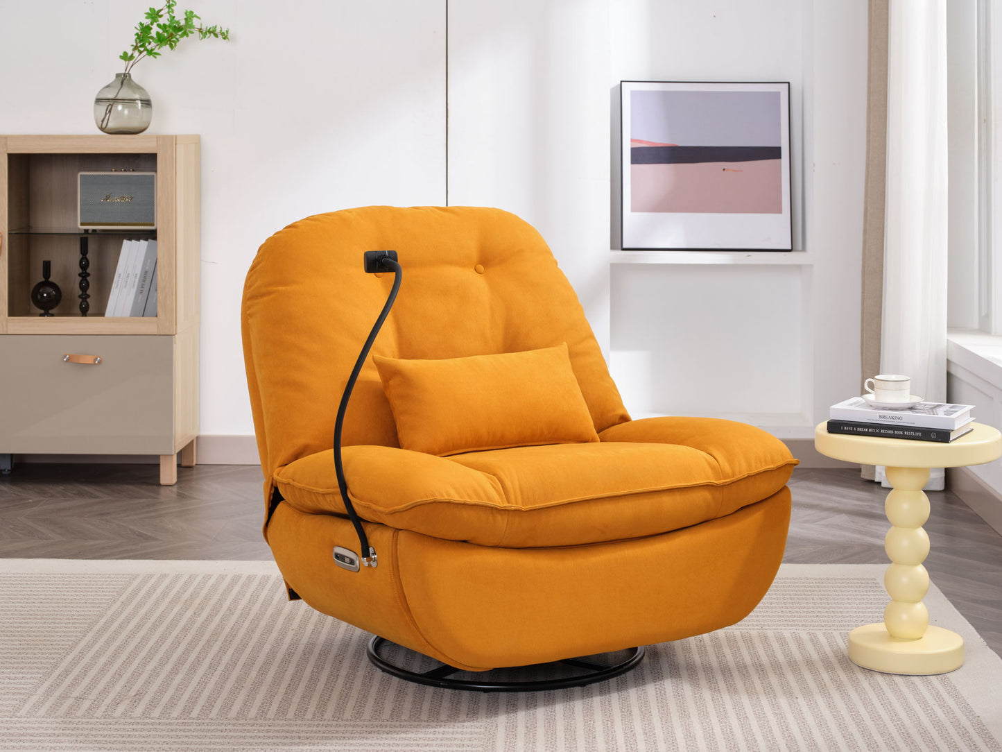 A modern Power Recliner Swivel Glider with USB charger and Bluetooth music sits on a beige rug in a bright room, next to a small round yellow table with books and a cup, with a bookcase and framed art in the background.