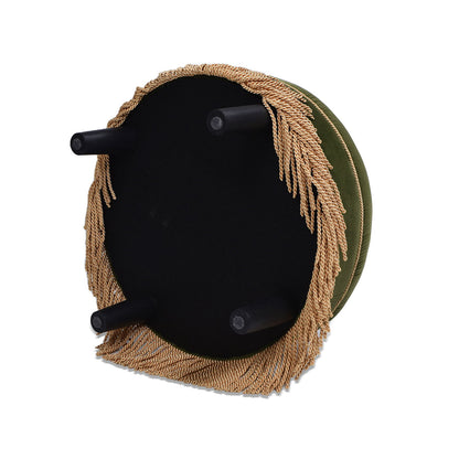 The Yolanda Round Upholstered Accent Ottoman is shown upside down, featuring a green cushion, four black legs, and decorative gold fringe around the base.