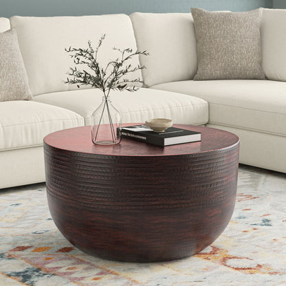 The Johnsen Handcrafted Metal Coffee Table sits on a patterned rug in front of a cream sectional sofa, topped with a glass vase holding branches, a black book, and a small decorative bowl.