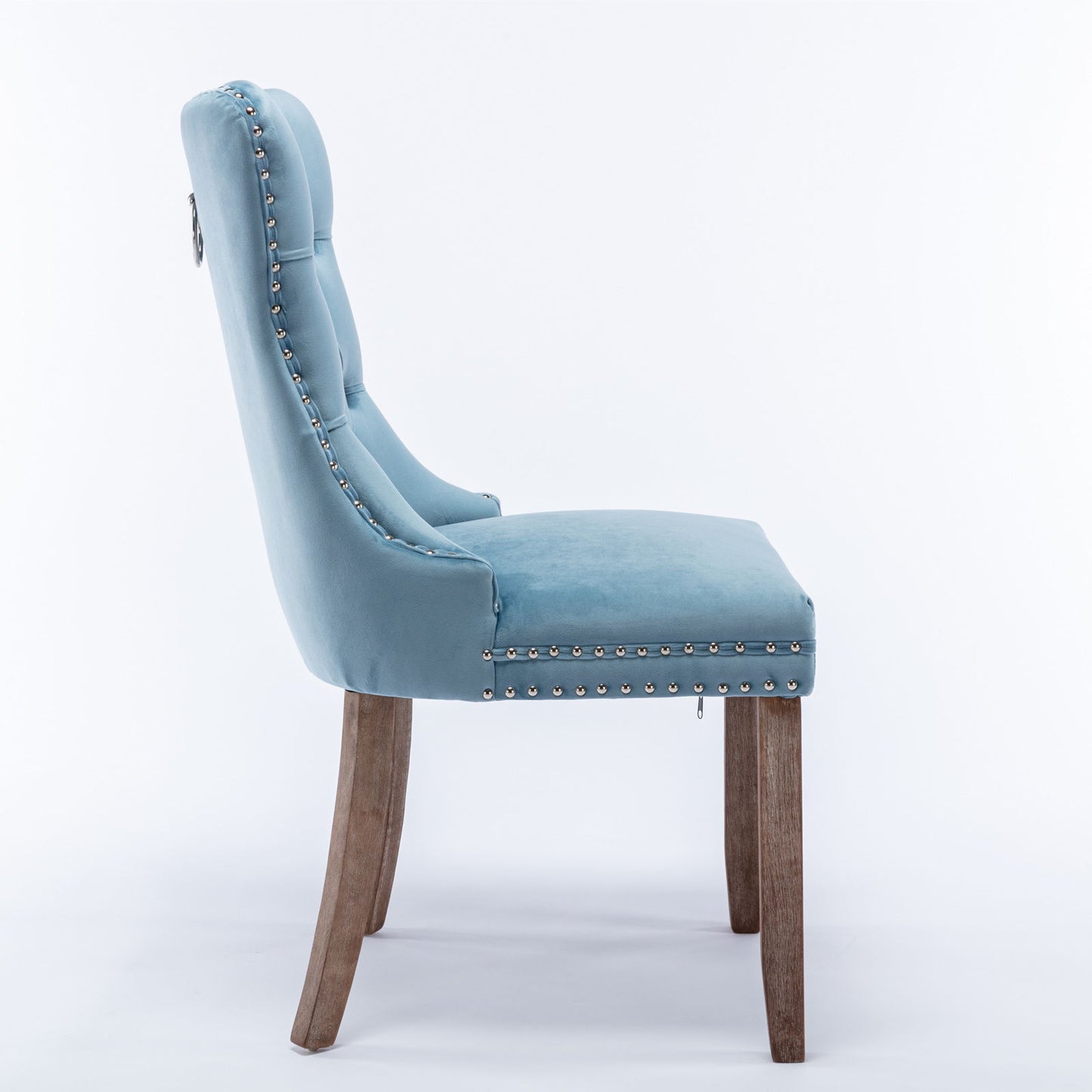Side view of the Nikki modern high-end tufted velvet dining chair in light blue, featuring nailhead trim and curved solid wood legs, set against a white background.