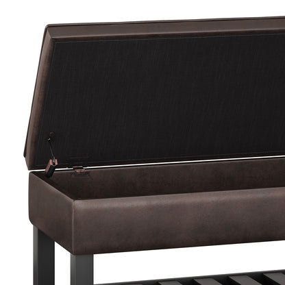 A close-up of the Cosmopolitan Storage Ottoman Bench with its lid open, showing an empty compartment. The bench features a brown cushion, dark metal frame, and a lower slatted open bottom shelf.
