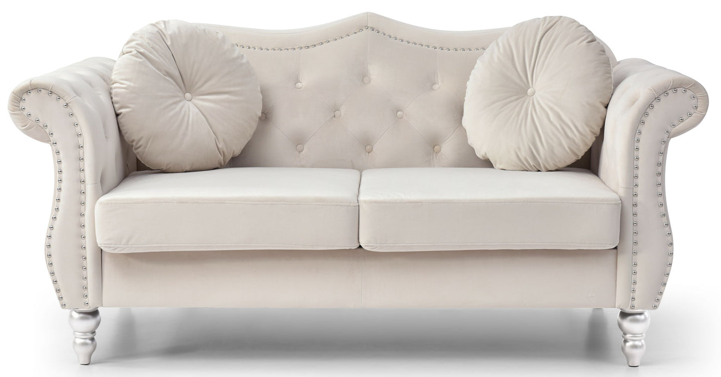 The Stylish Flared Arm Loveseat features plush light beige velvet, two seat cushions, a tufted backrest, curved armrests with silver nailhead trim, two round matching pillows, and short turned wooden legs.
