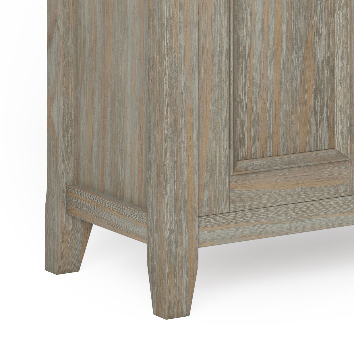 Close-up of the bottom corner of the Amherst - Handcrafted Low Storage Cabinet, featuring a light grayish-brown finish, two angled legs, and vertical wood grain texture.
