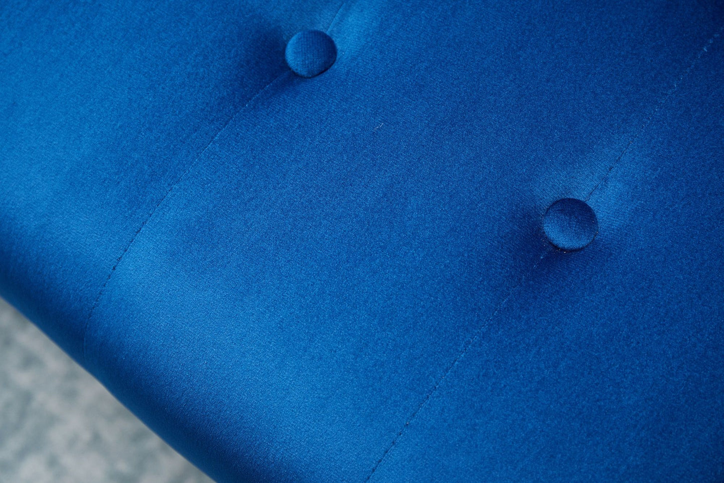Close-up of the Comfort Compact Design Sofa Bed's blue upholstered fabric, featuring two round, fabric-covered buttons in a tufted pattern. The smooth, slightly shiny surface adds a touch of elegance to the design.