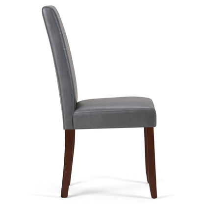 A side view of the Acadian - Upholstered Parson Dining Chair (Set of 2) shows its tall, padded gray leather backrest and seat, supported by four dark wooden legs.