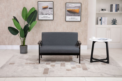 A modern living room featuring the Bahamas - Loveseat in gray, a potted plant, a white side table with a magazine and cup, boat-themed wall art, and a bookshelf in the background.