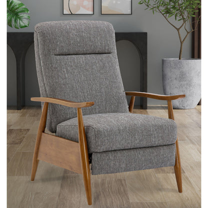 The Vaughn Push Back Recliner, featuring modern gray upholstery and solid hardwood legs, sits on a wooden floor in a stylish room with plants and abstract wall art in the background.